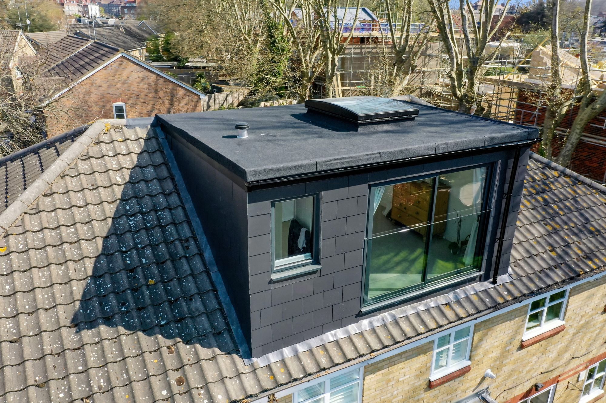 Roof Loft Conversion - Dormer Modern glass loft conversion on a sloped roof with garden views.